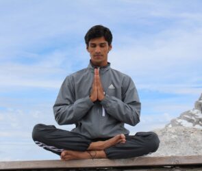 man meditating on brown wooden platform during daytime